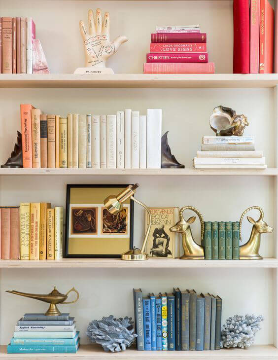 White bookshelves with groups of books styled in color co-ordination