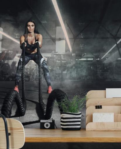 Krachtige gespierde vrouw fitnesstrainer doen vechttraining met touwen muurschildering Krachtige gespierde vrouw fitnesstrainer doen vechttraining met touwen muurschildering